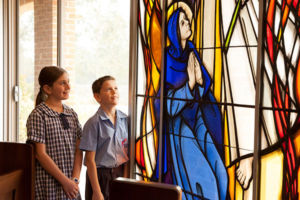 Two students admiring stained glass window in a church