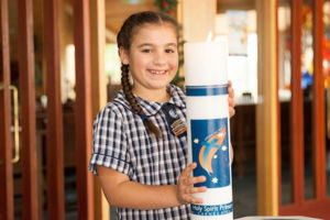 Young girl in uniform holding the school candle and smiling