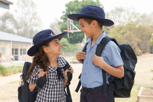 Two students with their school bags looking and smiling at each other